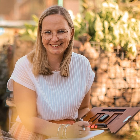 Meike sitzt im Garten und hält ihre Rednermappe in der Hand.